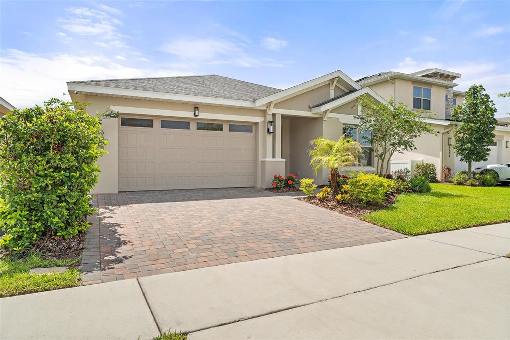 A single-story house with a beige exterior, a two-car garage, and a paved driveway — 6658 SYREETA LANE, ST CLOUD, FL