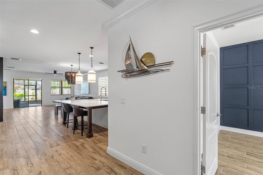 A view from a hallway into a kitchen with a large island and wood-look flooring — 6658 SYREETA LANE, ST CLOUD, FL