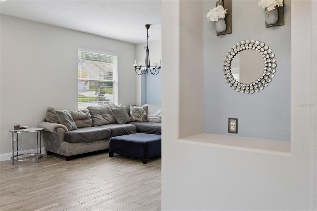 A living room with a gray sectional sofa, a blue ottoman, and a wall niche — 465 ROB ROY DRIVE, CLERMONT, FL
