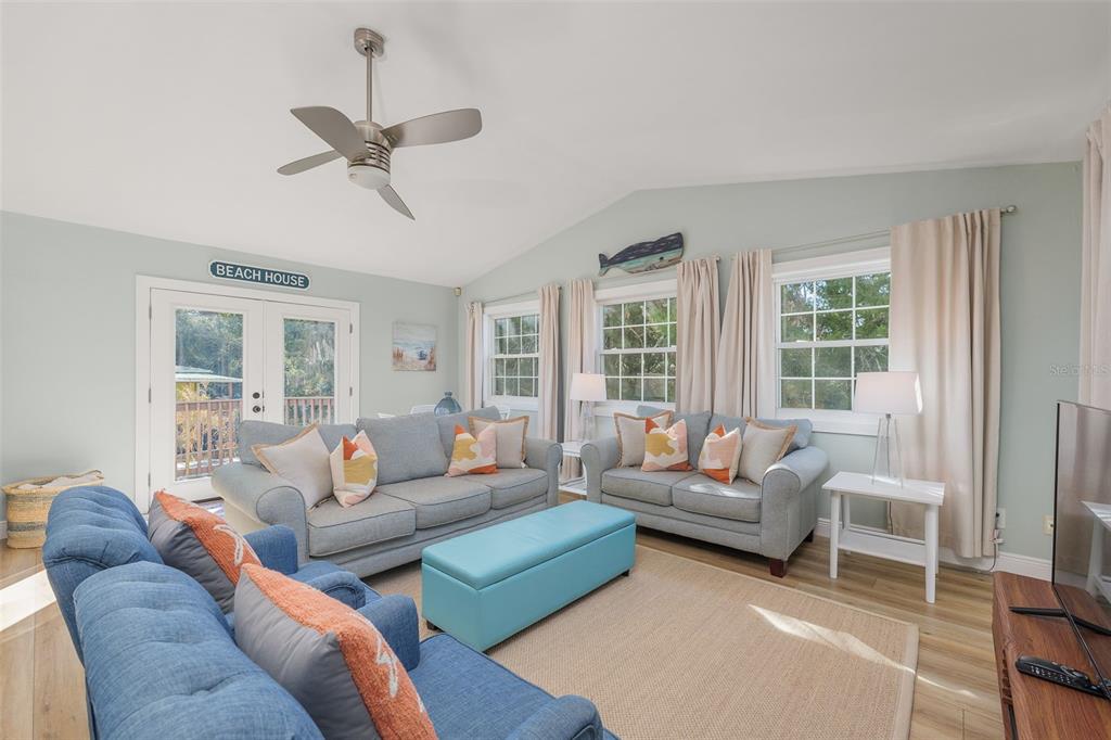 A living room features light blue walls, two gray sofas, a blue ottoman, and a ceiling fan — 287 BOULEVARD DES PINS, ST AUGUSTINE, FL