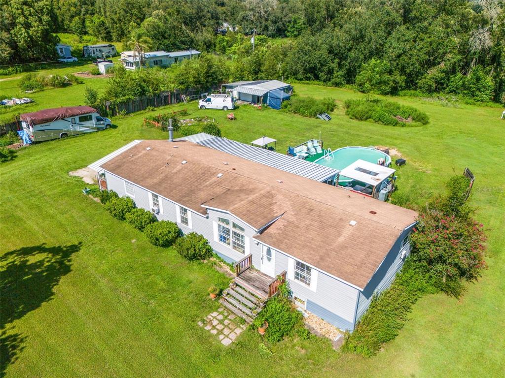 An aerial view of a light blue manufactured home with a pool and large yard — 8512 HAMSTER DRIVE, ZEPHYRHILLS, FL