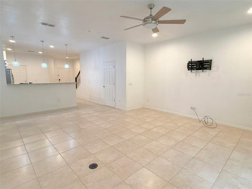 An open-concept living area features light tile flooring, a ceiling fan, and a wall-mounted television bracket — 1288 PAVIA DRIVE, APOPKA, FL