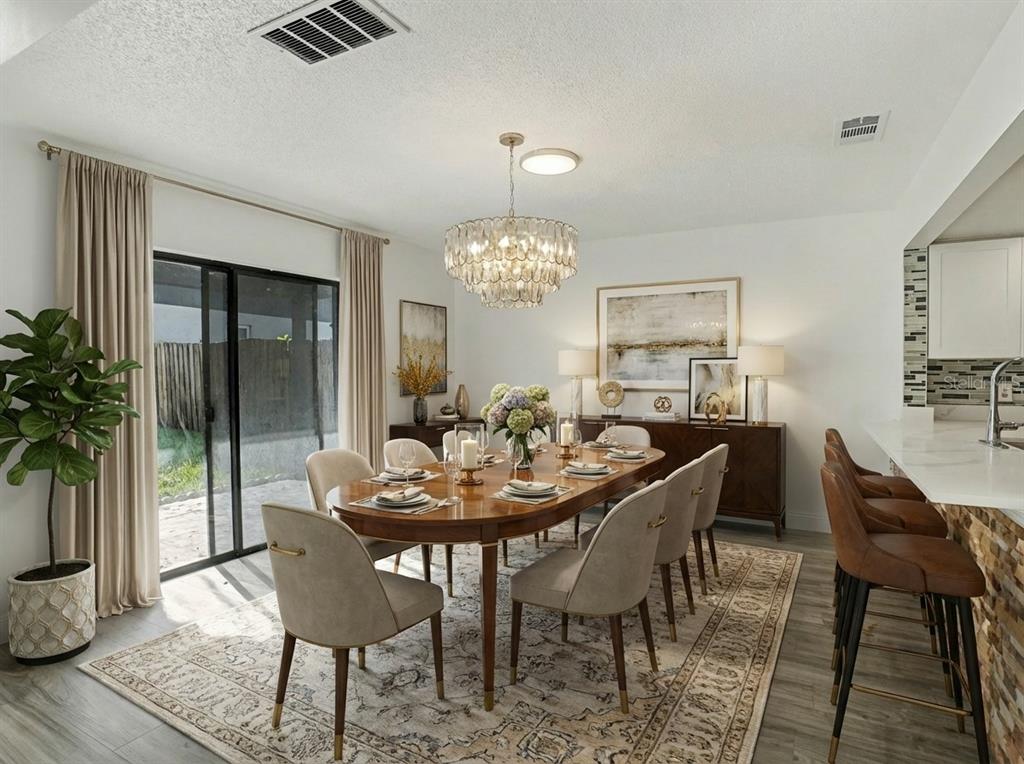 A dining room features an oval wooden table, upholstered chairs, a crystal chandelier, and sliding doors — 1196 INDIAN BLUFF, APOPKA, FL