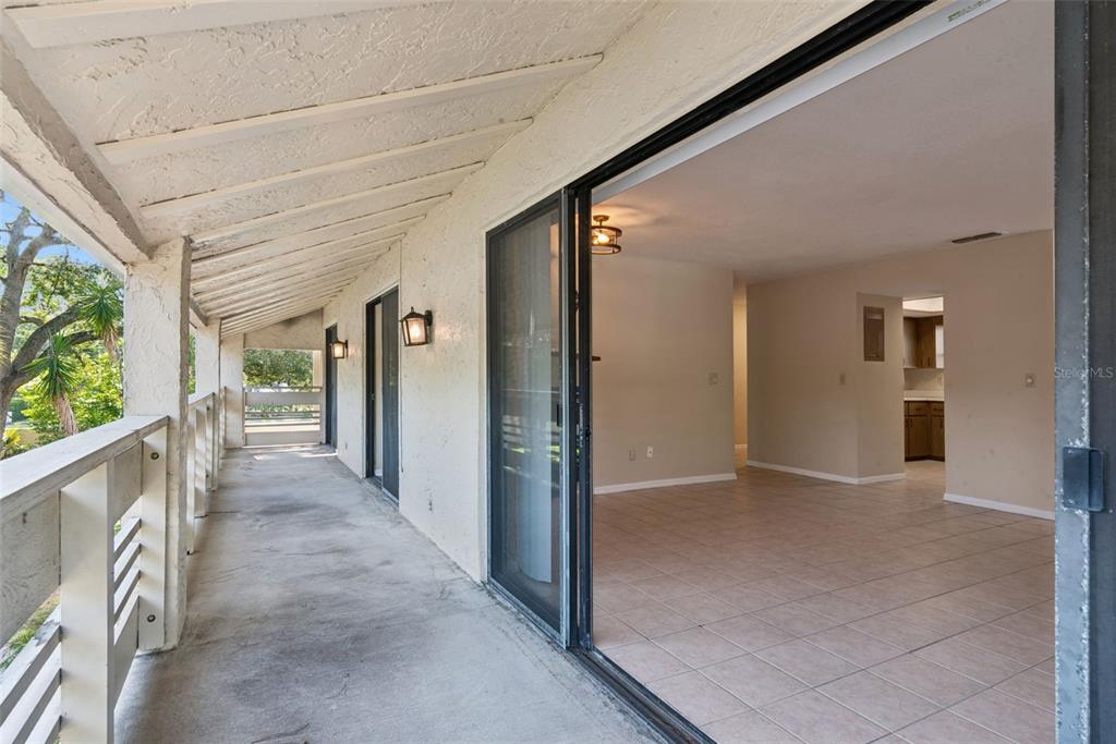 A covered balcony with concrete flooring overlooks a tiled interior living area through sliding glass doors — 445 S NETHERWOOD CRESCENT UNIT 2, ALTAMONTE SPRINGS, FL