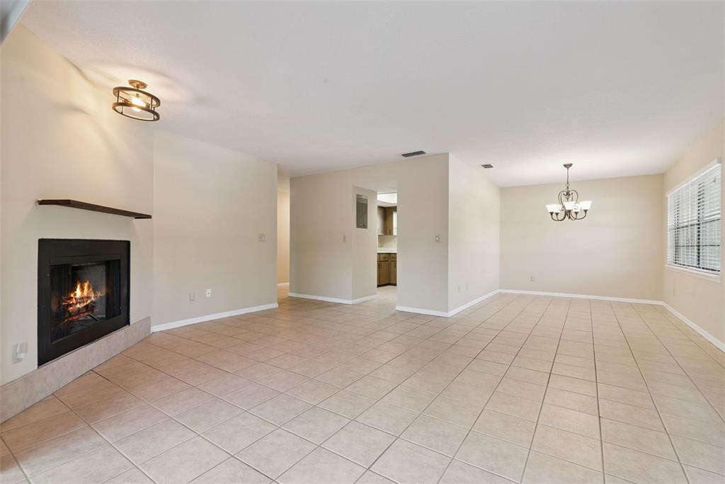 A living room with tile flooring, a fireplace, and a dining area with a chandelier — 445 S NETHERWOOD CRESCENT UNIT 2, ALTAMONTE SPRINGS, FL
