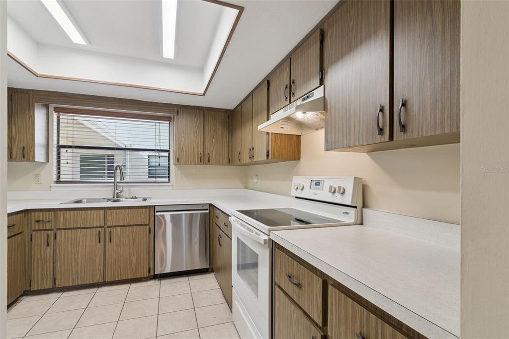A kitchen with wood cabinets, white countertops, a stainless steel dishwasher, and a white stove — 445 S NETHERWOOD CRESCENT UNIT 2, ALTAMONTE SPRINGS, FL
