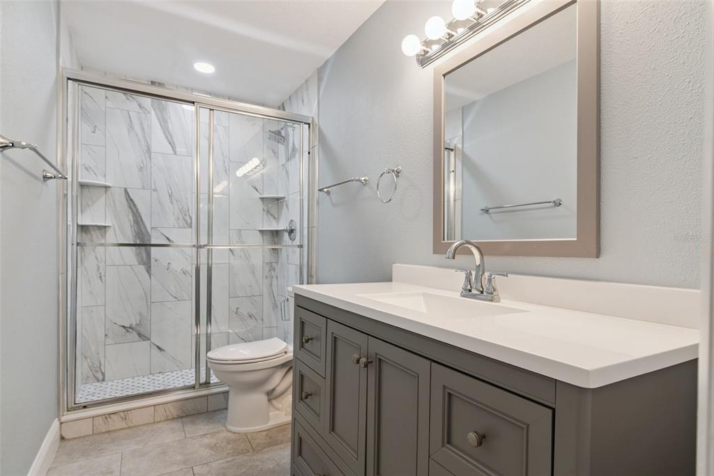 A bathroom with a gray vanity, white countertop, and a walk-in shower with marble-look tile — 445 S NETHERWOOD CRESCENT UNIT 2, ALTAMONTE SPRINGS, FL