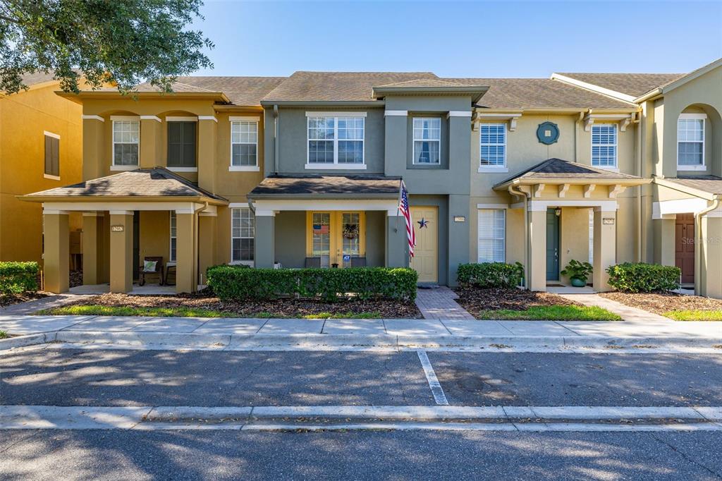 A row of three-story townhomes with covered porches and a shared sidewalk in front — 12966 VENNETTA WAY, WINDERMERE, FL