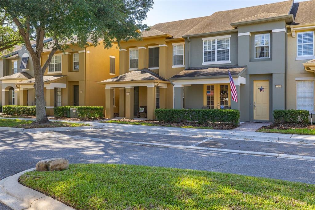 A row of multi-story townhouses with tan and olive-green stucco exteriors and covered front porches — 12966 VENNETTA WAY, WINDERMERE, FL