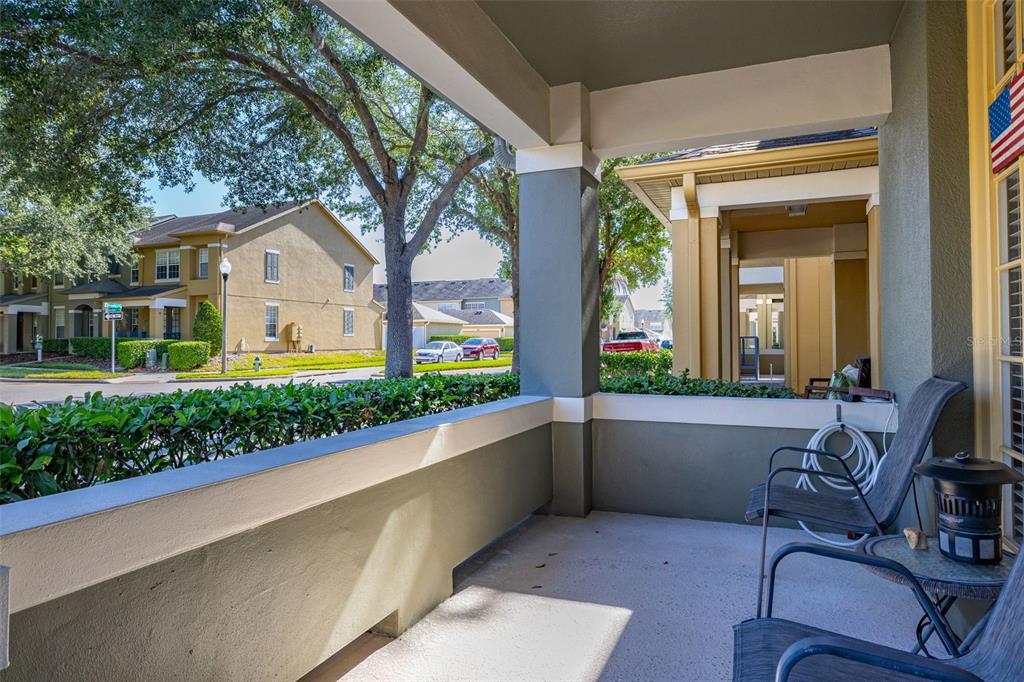 A covered porch with a concrete floor, two chairs, and a view of neighboring buildings — 12966 VENNETTA WAY, WINDERMERE, FL