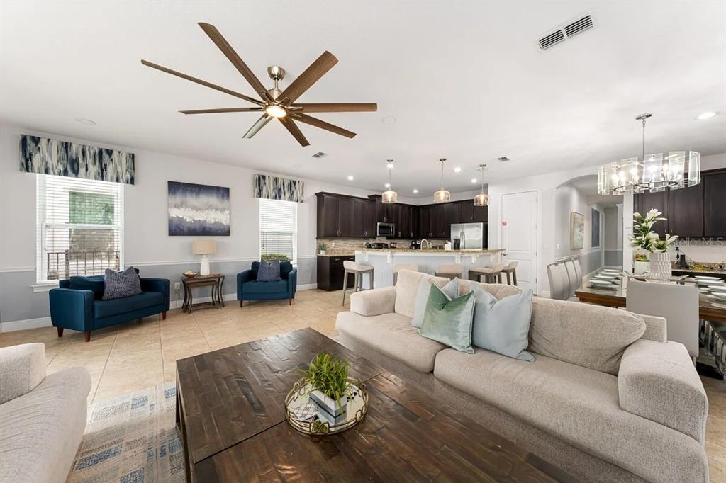 A spacious open-concept living room features a large sectional, dark wood coffee table, and kitchen — 795 GOLDEN BEAR DRIVE, REUNION, FL
