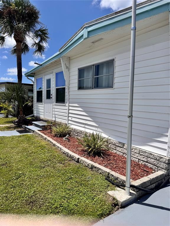 The exterior of a white mobile home features a stone-bordered garden bed and a flagpole — 6100 62ND AVENUE N UNIT 43, PINELLAS PARK, FL