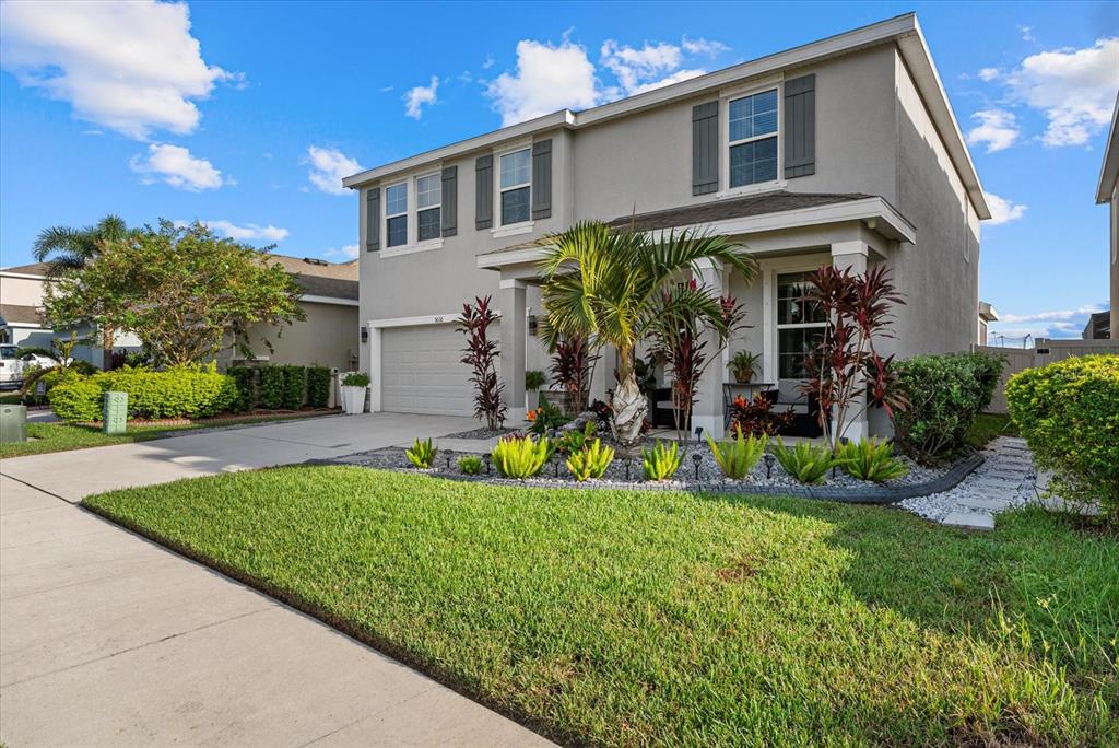 A two-story suburban house with a gray stucco exterior, a garage, and landscaped front yard — 5030 JACKEL CHASE DRIVE, WIMAUMA, FL