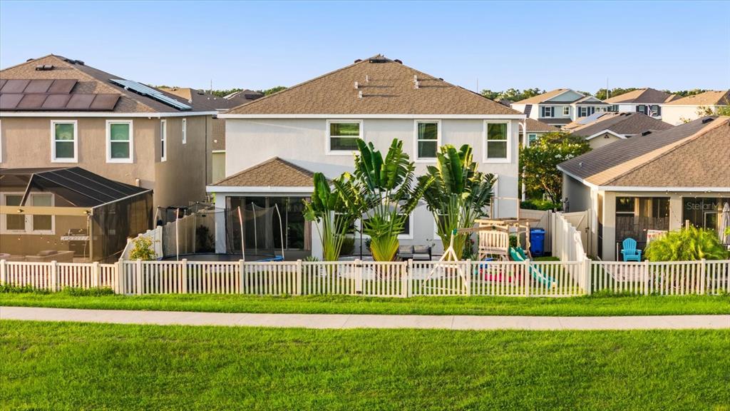 The rear exterior of a two-story house features a fenced backyard with a playground — 5030 JACKEL CHASE DRIVE, WIMAUMA, FL