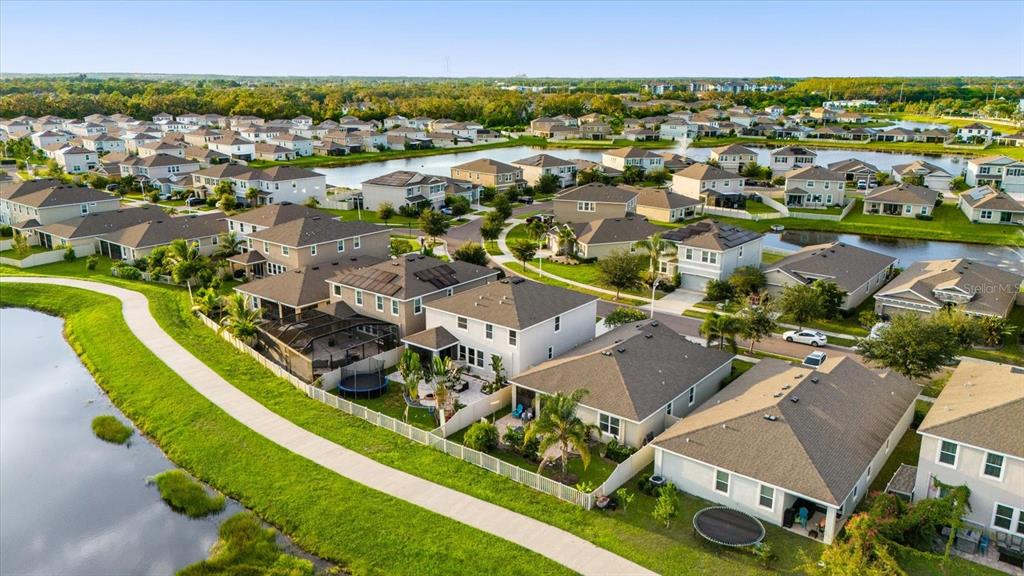 An aerial view shows a suburban neighborhood with houses, backyards, and a winding pond — 5030 JACKEL CHASE DRIVE, WIMAUMA, FL