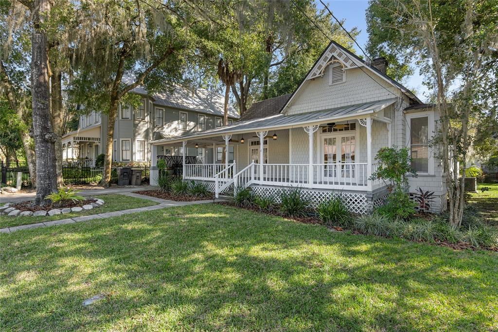 A light-colored cottage with a wrap-around porch and shingle siding sits on a grassy lot — 818 SE 3RD STREET, OCALA, FL