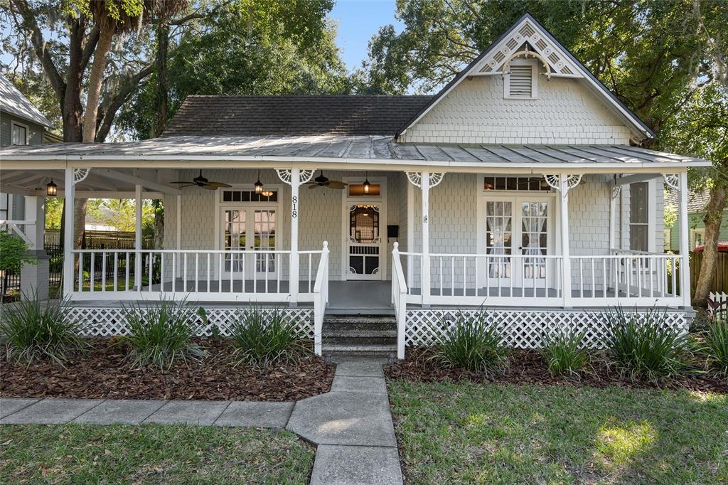 A light gray house with a wrap-around porch, white railings, and a metal roof — 818 SE 3RD STREET, OCALA, FL