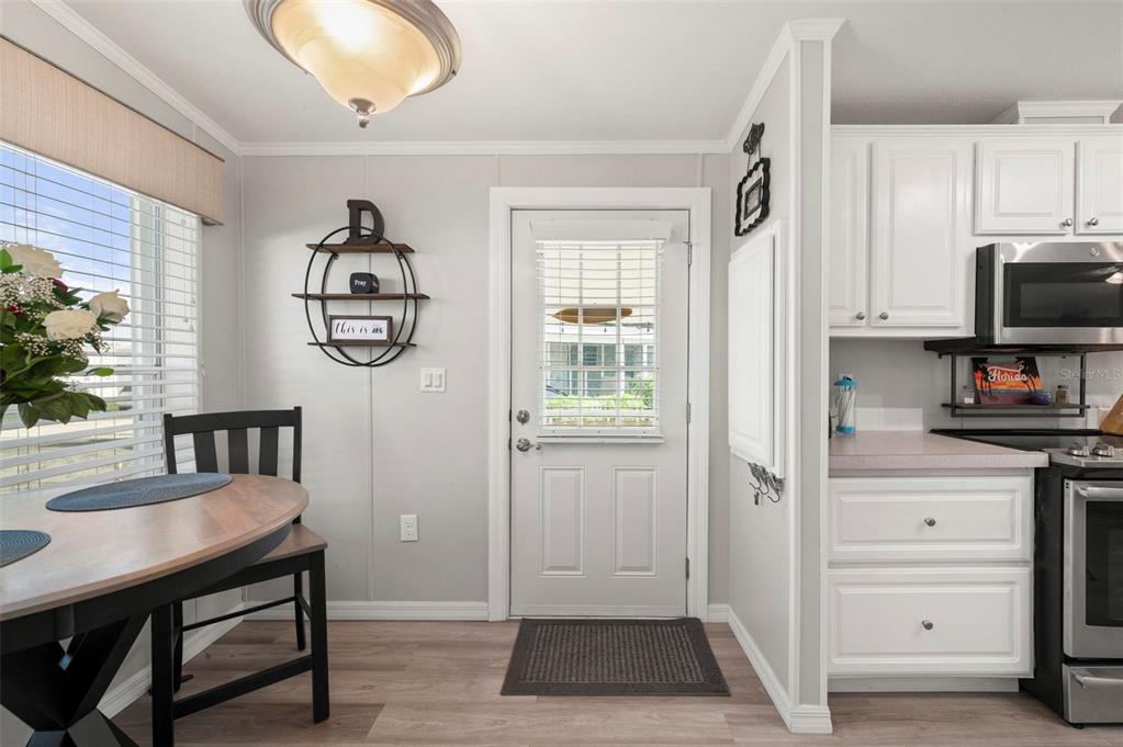 A kitchen and dining area featuring white cabinets, a round table, and a white door — 1000 KINGS HIGHWAY UNIT 262, PORT CHARLOTTE, FL