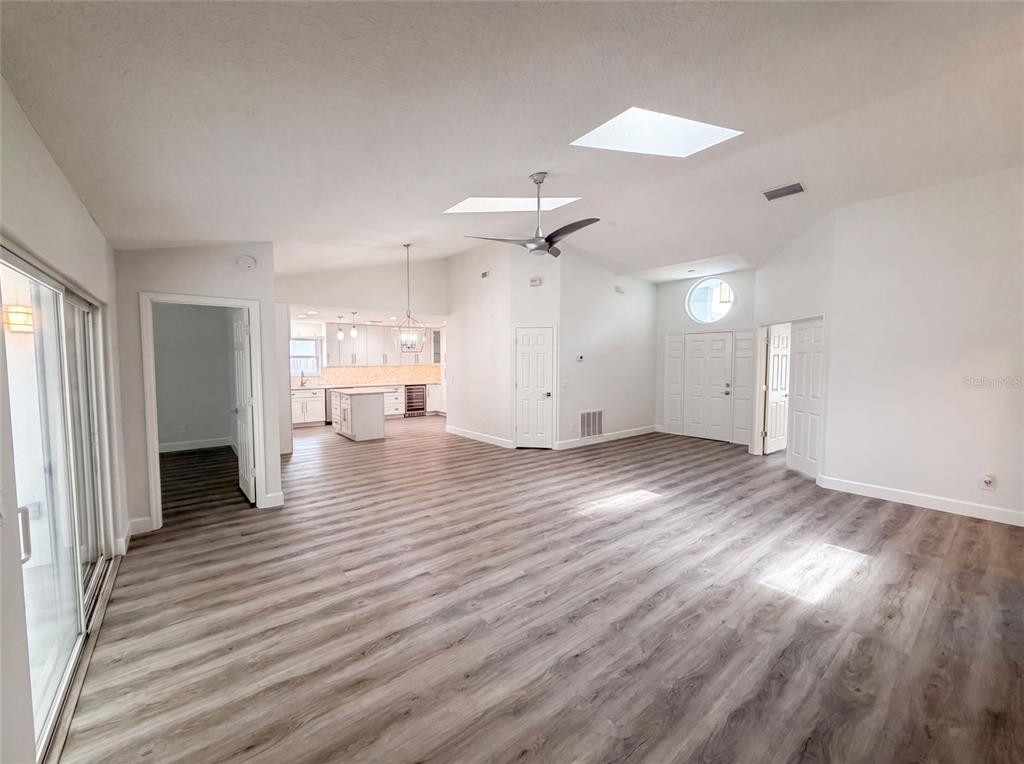 A spacious living area with wood-look flooring, vaulted ceilings, skylights, and an open kitchen — 1340 SASSAFRAS AVENUE, ALTAMONTE SPRINGS, FL