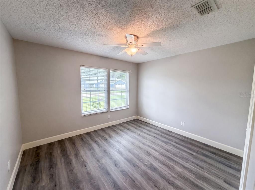 An empty bedroom features light gray walls, wood-look flooring, a ceiling fan, and two windows — 1340 SASSAFRAS AVENUE, ALTAMONTE SPRINGS, FL
