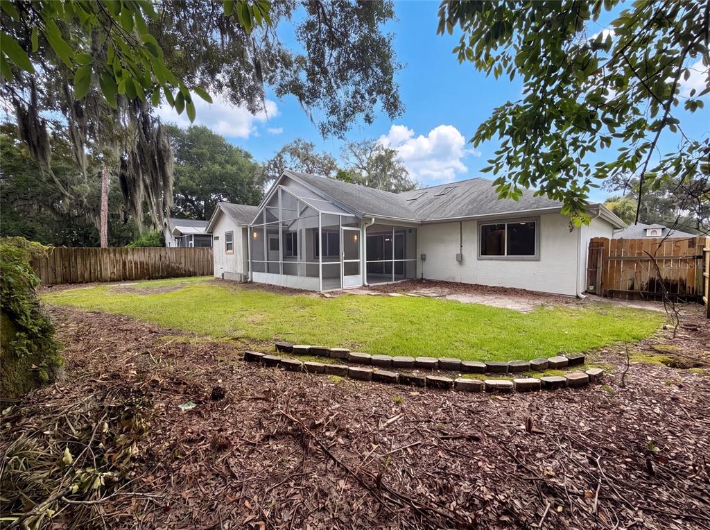 The backyard features a screened-in porch, a grassy lawn, and a wooden privacy fence — 1340 SASSAFRAS AVENUE, ALTAMONTE SPRINGS, FL