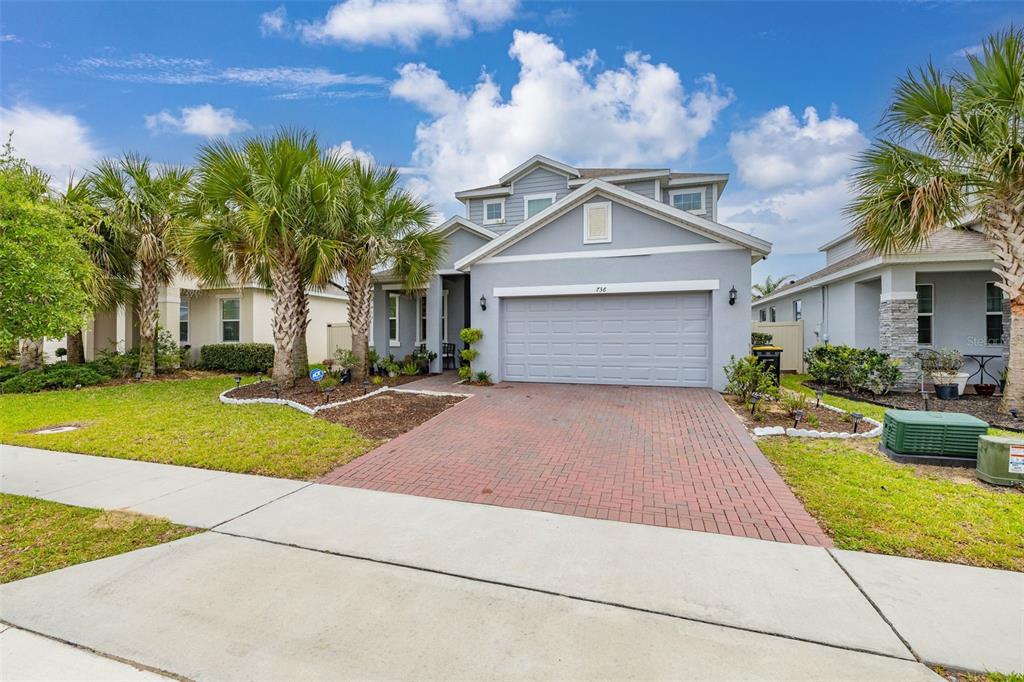 A two-story gray house with a brick driveway and palm trees in the front yard — 736 GRAZIE LOOP, DAVENPORT, FL