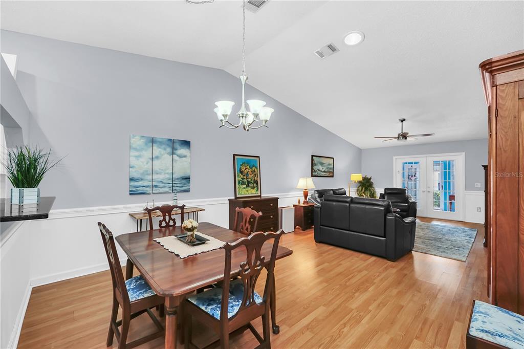 A dining area with a wooden table and chairs opens into a living room space — 909 ILLINOIS AVENUE, ST CLOUD, FL