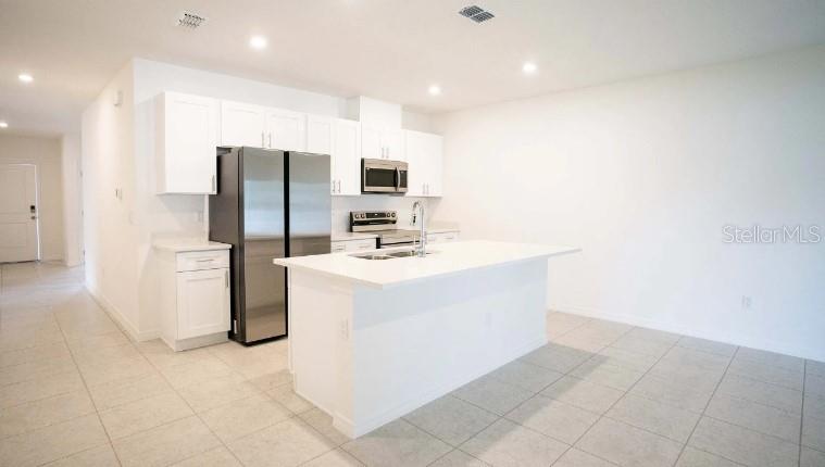 A modern kitchen features white cabinetry, stainless steel appliances, and a central island — 612 BROADOAK DRIVE, DUNDEE, FL