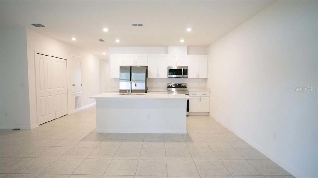 A kitchen features white cabinets, stainless steel appliances, a center island, and tiled flooring — 612 BROADOAK DRIVE, DUNDEE, FL