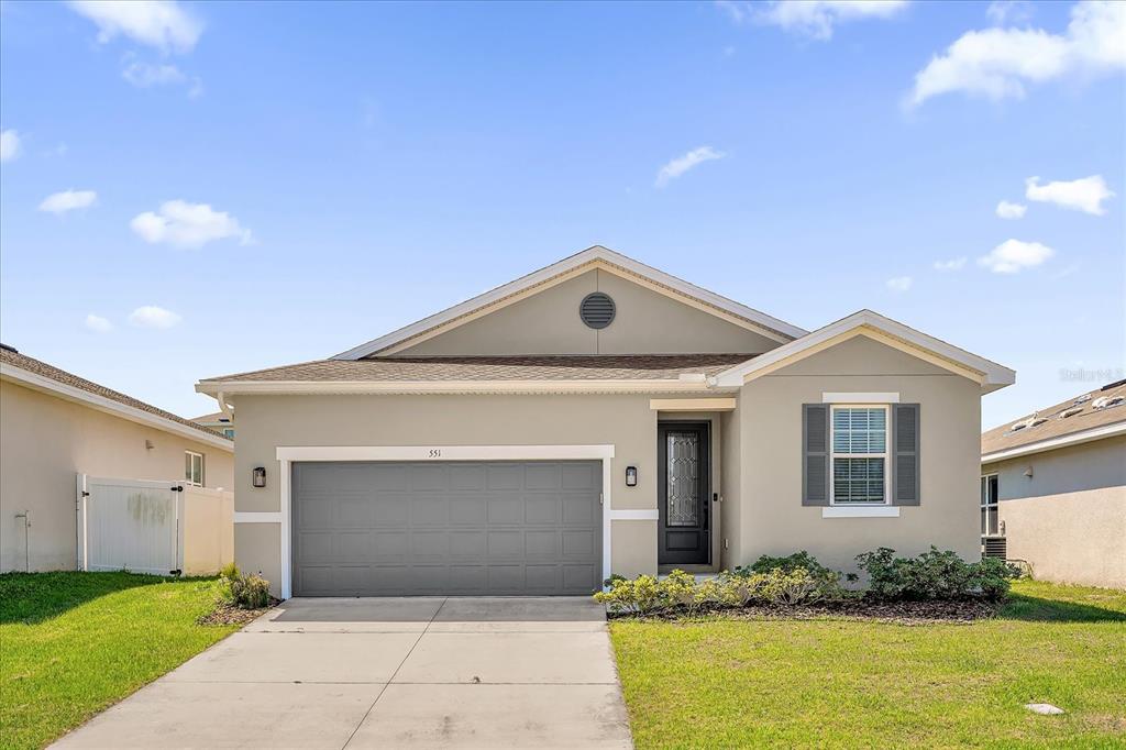 An aerial view of a single-story suburban house with a gray garage and tan siding — 551 LAKE SMART BOULEVARD, WINTER HAVEN, FL