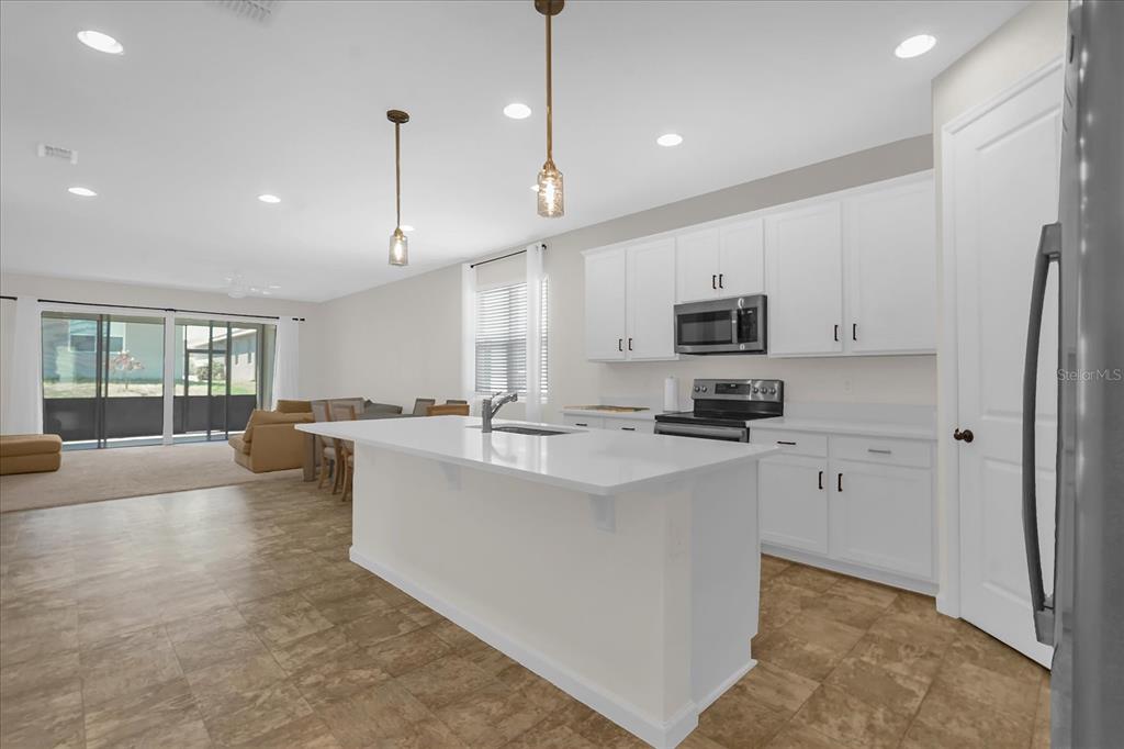 A living room features tan sectional seating, carpeted flooring, and sliding glass doors to a patio — 551 LAKE SMART BOULEVARD, WINTER HAVEN, FL