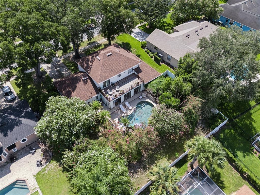 An aerial view shows a two-story house with a brown roof, deck, and backyard pool — 9130 DOLLANGER COURT, ORLANDO, FL