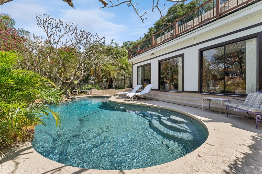 A swimming pool sits on a patio next to a house with sliding glass doors — 9130 DOLLANGER COURT, ORLANDO, FL