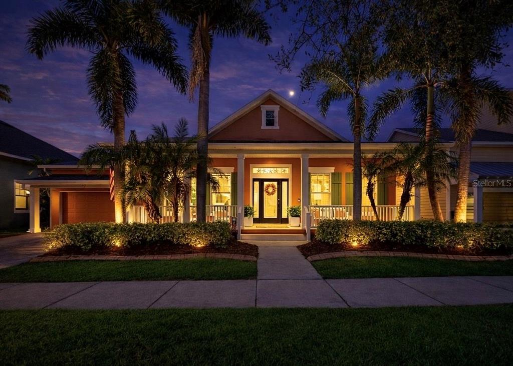 A single-story orange house with a two-car garage, front porch, and palm trees — 5715 SEA TROUT PLACE, APOLLO BEACH, FL