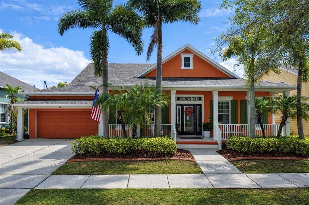 A single-story orange house with a front porch, palm trees, and a landscaped yard — 5715 SEA TROUT PLACE, APOLLO BEACH, FL