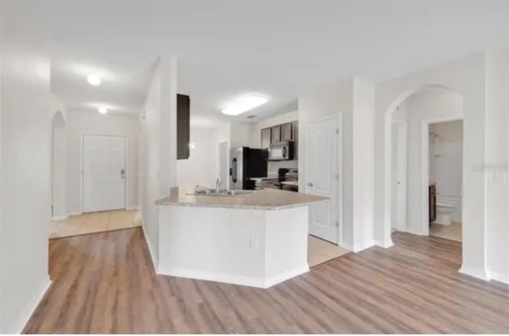 An open-concept kitchen with a breakfast bar, light-colored walls, and wood-look flooring — 724 LAKE CUMMINGS BOULEVARD, LAKE ALFRED, FL
