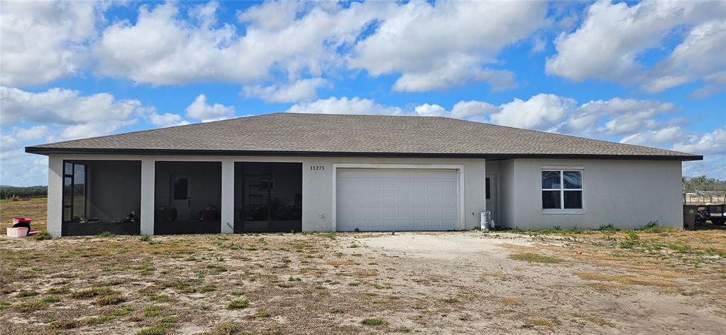 A single-story house with a screened-in porch, a two-car garage, and a light-colored exterior — 11275 WHOOPERS RUN, CLERMONT, FL
