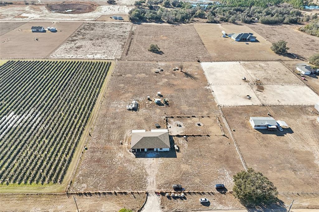An aerial view shows a rural property with a house, outbuildings, and agricultural fields — 11275 WHOOPERS RUN, CLERMONT, FL