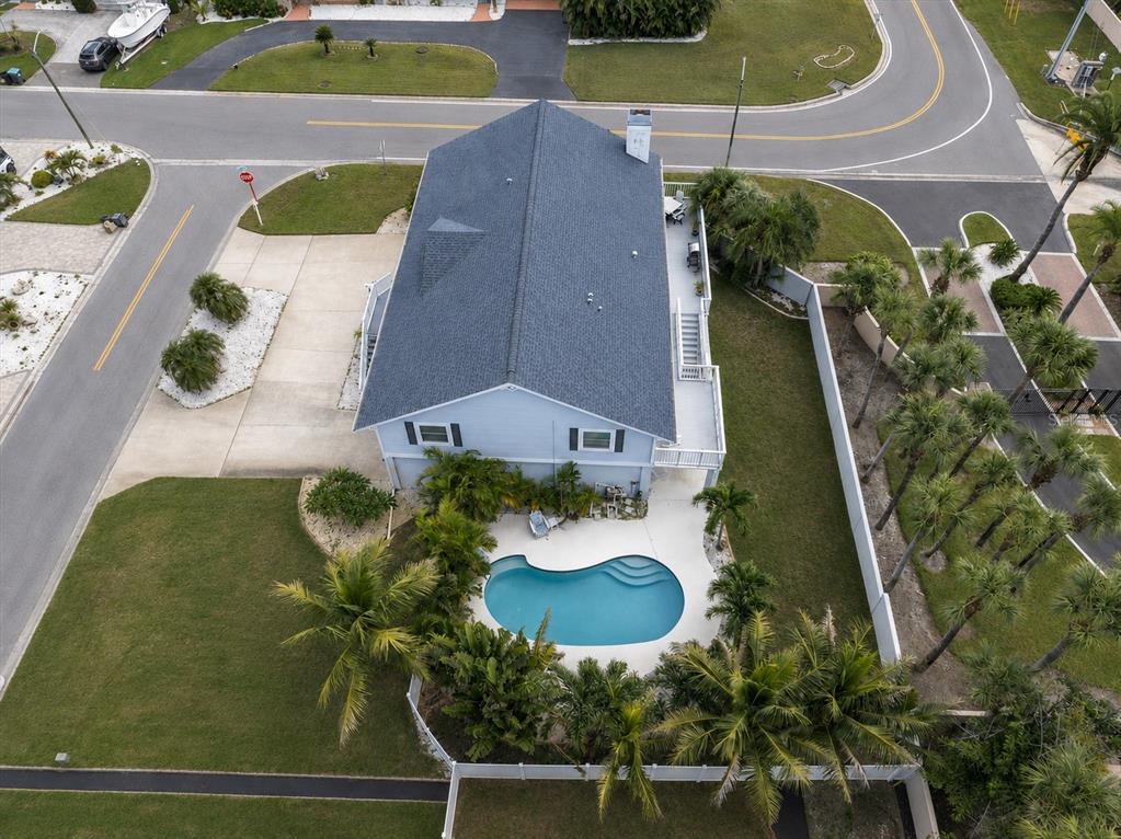 A two-story house with a garage, white stairs, and landscaping sits on a grassy lot — 6501 MOCKINGBIRD WAY S, GULFPORT, FL