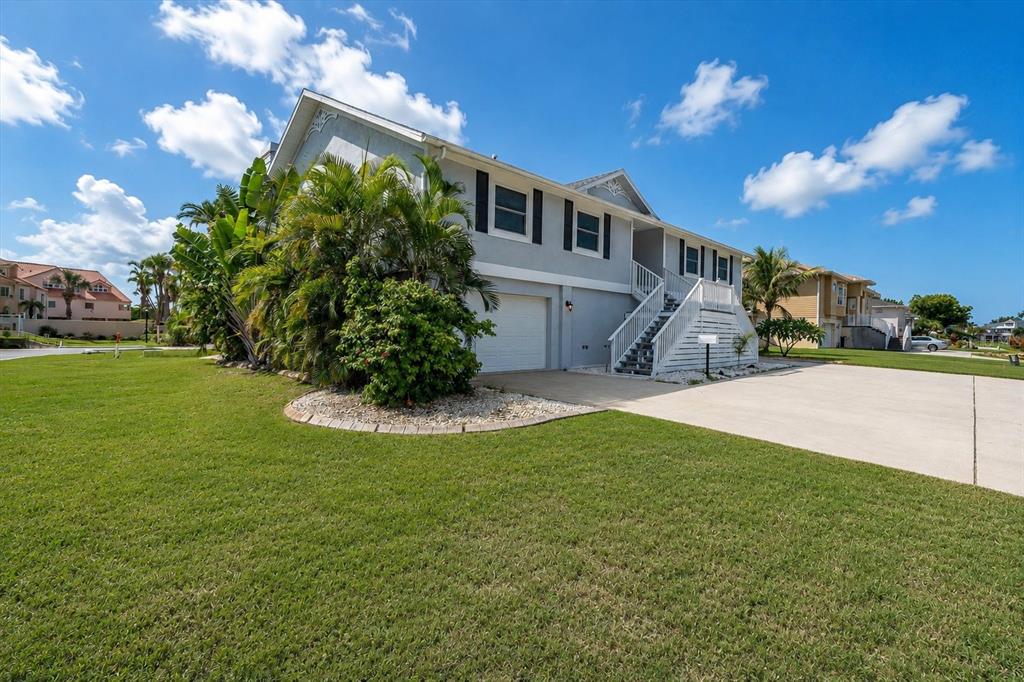 An entryway features light wood-look flooring, a round pedestal table with flowers, and double front doors — 6501 MOCKINGBIRD WAY S, GULFPORT, FL