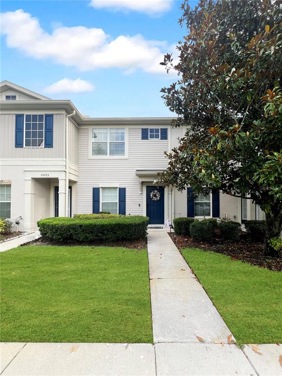 A two-story townhouse features light siding, blue shutters, and a front walkway with landscaping — 15767 STABLE RUN DRIVE, SPRING HILL, FL
