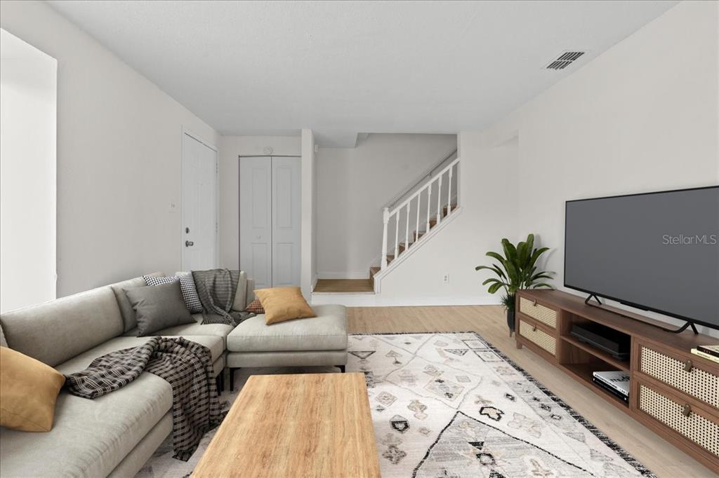 A living room features a sectional sofa, a wooden coffee table, and stairs leading upward — 4945 SANOMA VILLAGE UNIT B, ORLANDO, FL