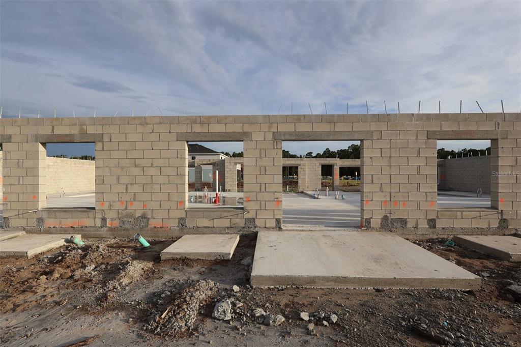 A construction site shows a concrete block wall with window and door openings on a foundation — 6067 FELLOW WAGON WAY, ORLANDO, FL