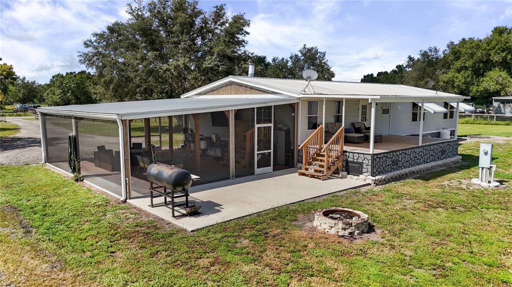 A manufactured home features a large screened-in porch, a concrete patio, and a fire pit — 4480 FORT SIMMONS AVENUE, LABELLE, FL
