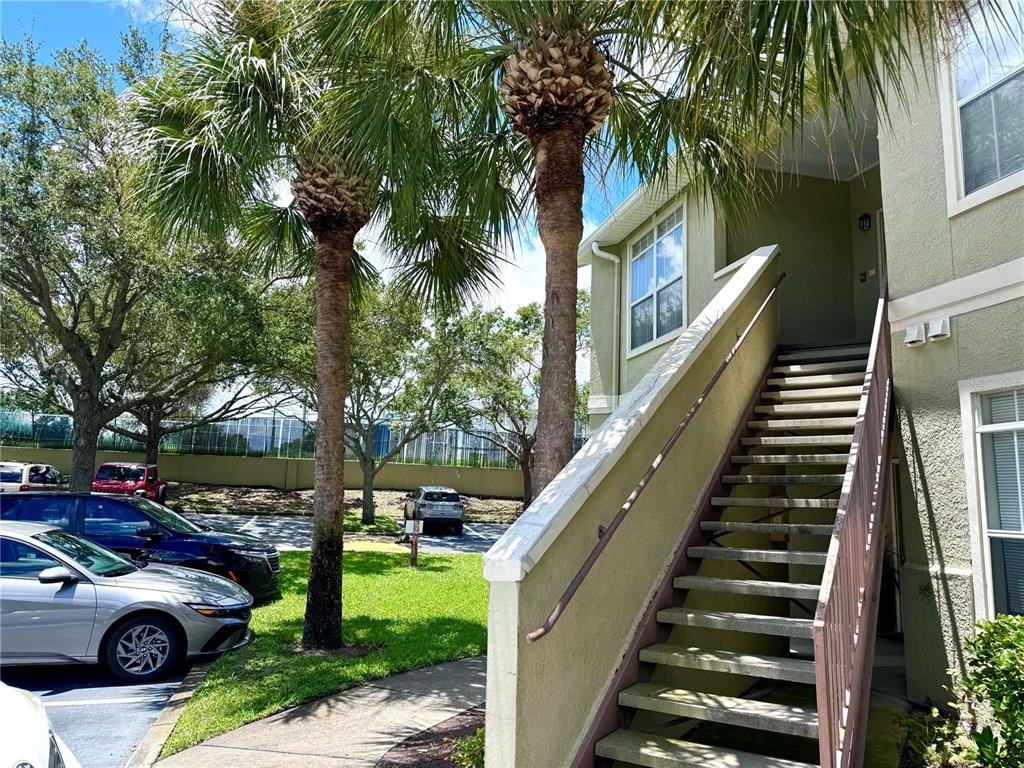 An exterior view of a multi-story apartment building with stairs leading to an upper entrance — 1238 S MISSOURI AVENUE UNIT 102, CLEARWATER, FL
