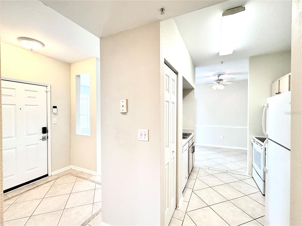 A view of an entryway leading into a kitchen with tiled floors and white appliances — 1238 S MISSOURI AVENUE UNIT 102, CLEARWATER, FL