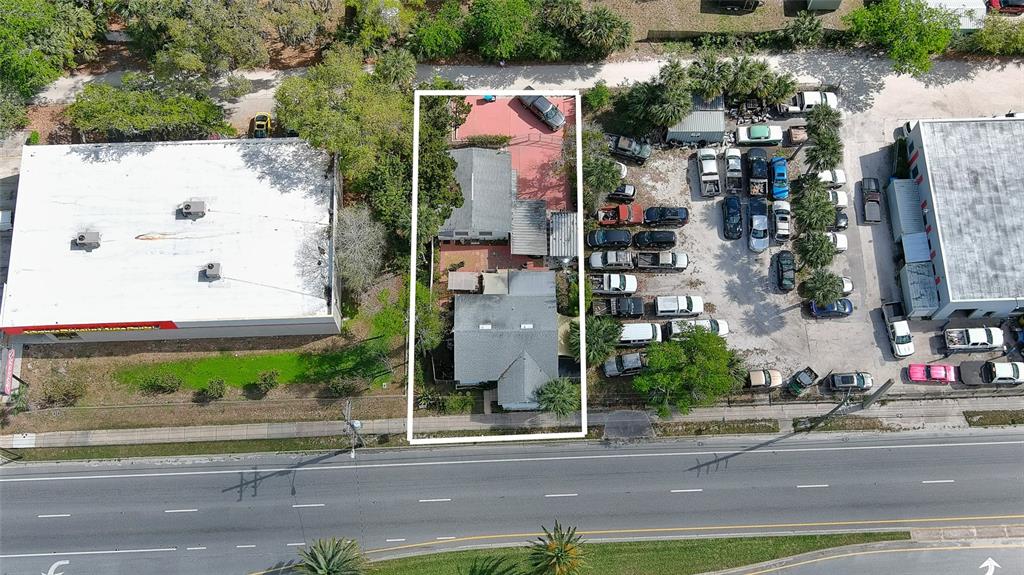 An aerial view shows a residential lot with two buildings situated between two commercial properties — 607 N DIXIE FREEWAY, NEW SMYRNA BEACH, FL