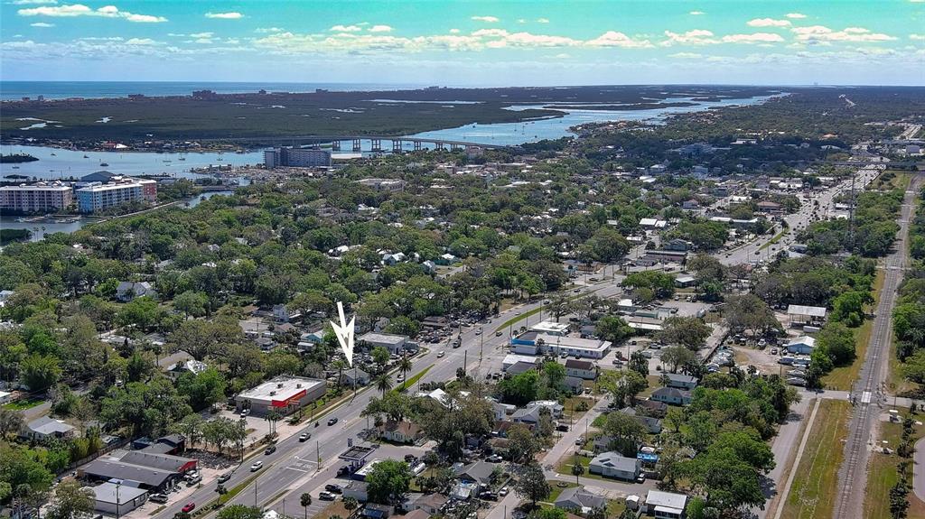 An aerial view shows a commercial building with a white arrow pointing toward it — 607 N DIXIE FREEWAY, NEW SMYRNA BEACH, FL