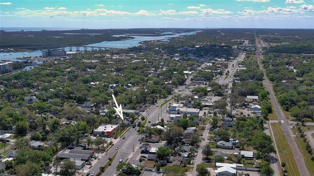 An aerial view shows a commercial building with a white arrow pointing toward it — 607 N DIXIE FREEWAY, NEW SMYRNA BEACH, FL