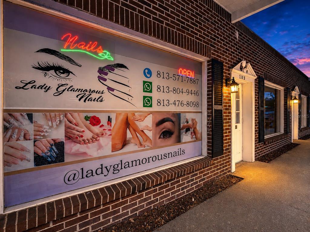 The exterior of a brick building features a large window display for Lady Glamorous Nails — 110 LITHIA PINECREST ROAD UNIT D, BRANDON, FL